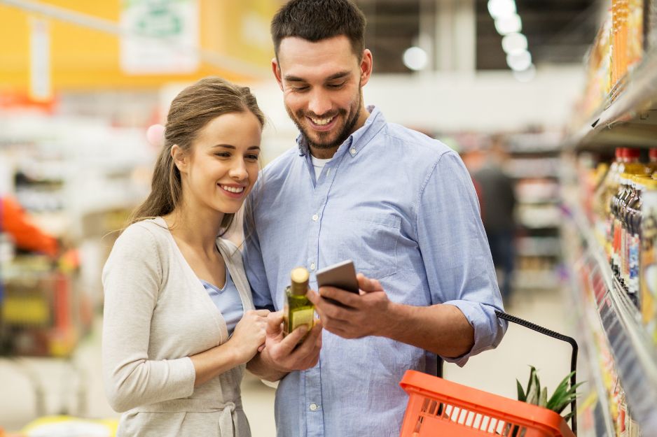 Couple compares prices on smartphone in supermarket